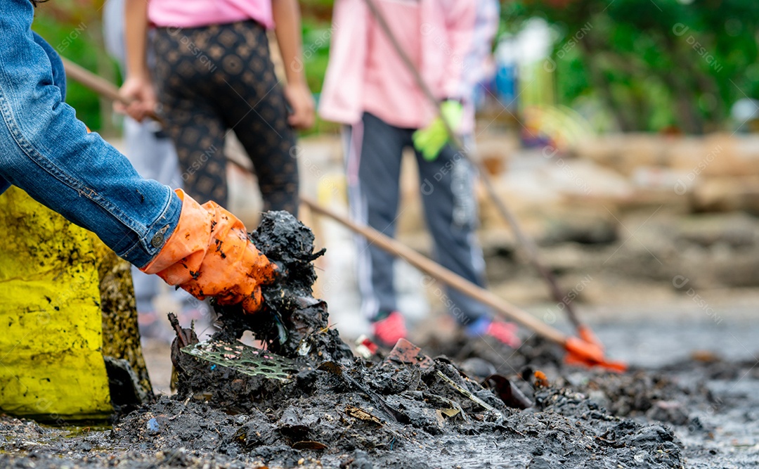 Voluntários adultos e crianças coletando lixo na praia do mar
