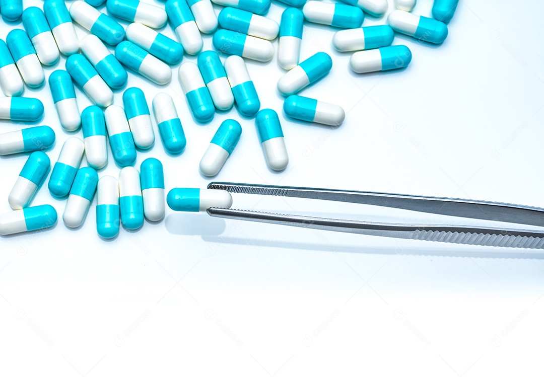 O fórceps escolhe a cápsula branco-azul do grupo de comprimidos da cápsula.