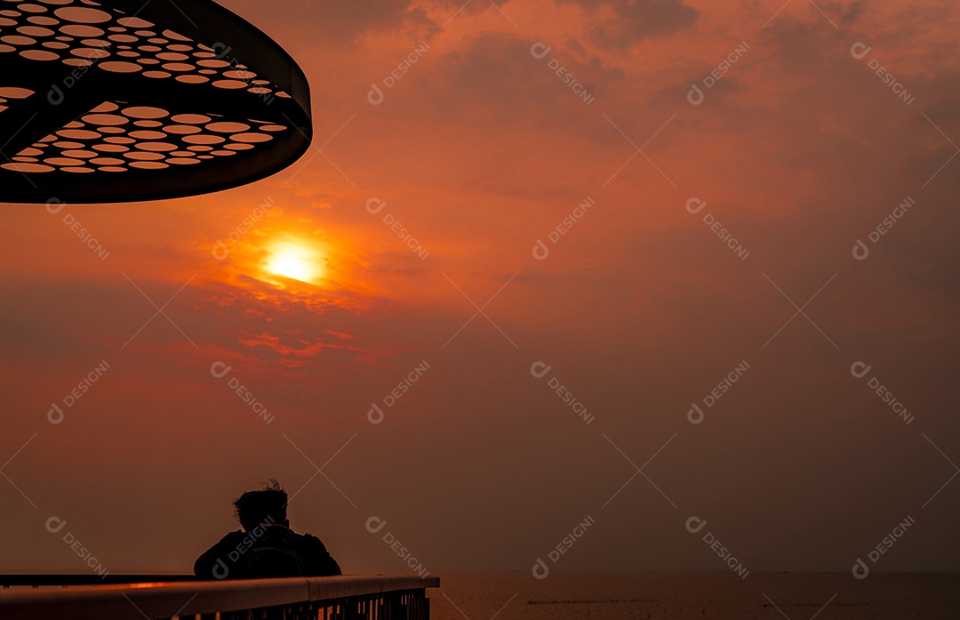 Mochileiro assistindo o pôr do sol sobre o mar no mirante de Laem Thaen