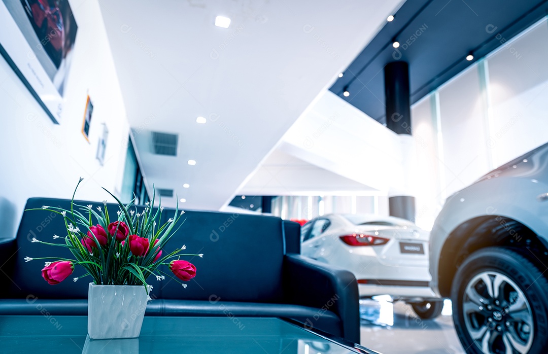 Flores vermelhas falsas em vaso na mesa no showroom de carros modernos.