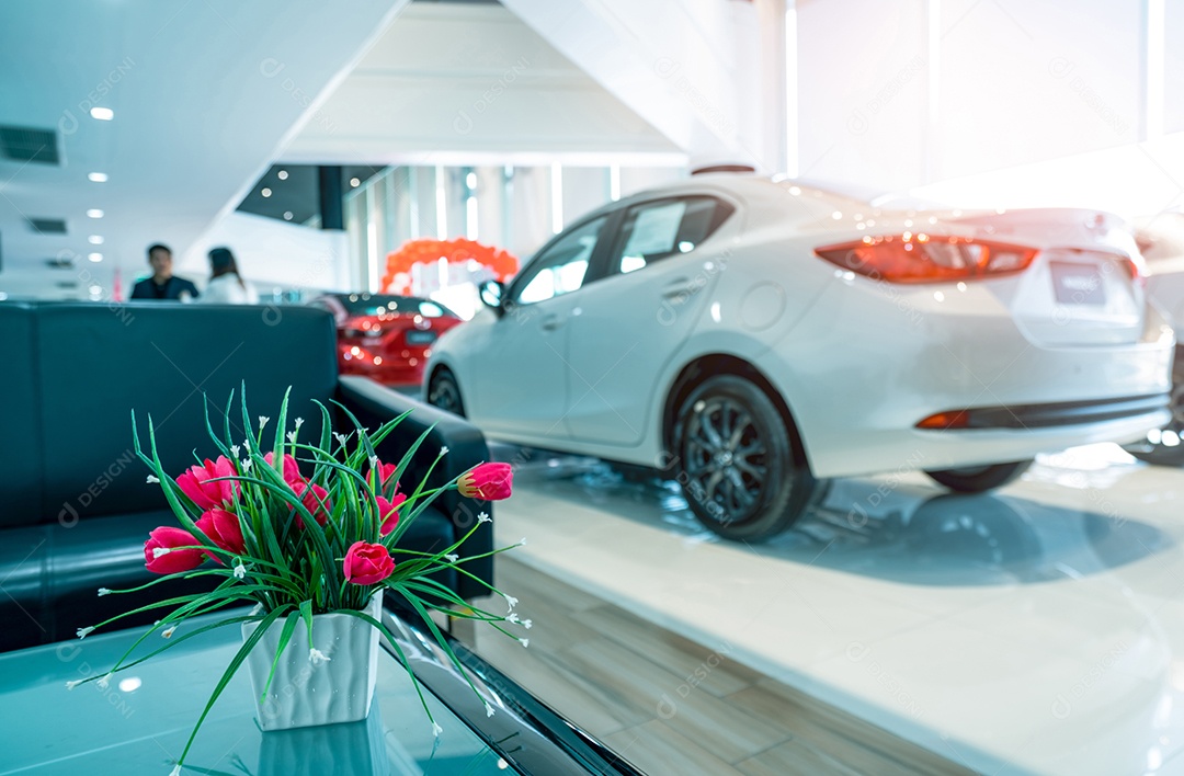 Flores vermelhas falsas em vaso na mesa no showroom de carros modernos.