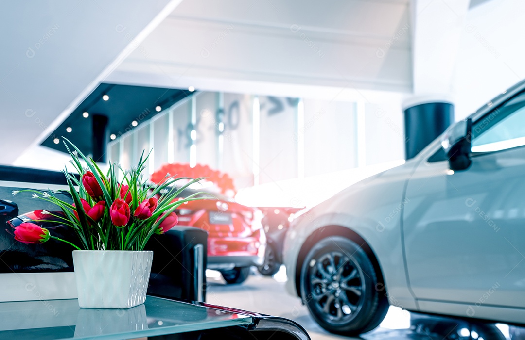 Flores vermelhas falsas em vaso na mesa no showroom de carros modernos.