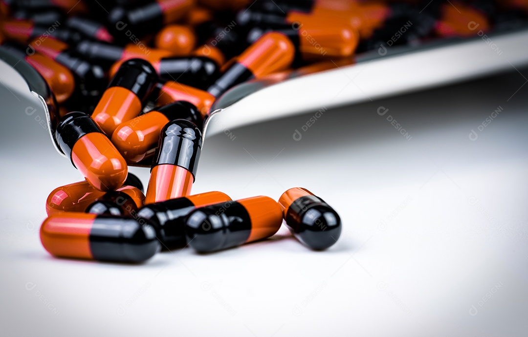 Comprimidos de cápsula laranja e preto na bandeja de drogas.