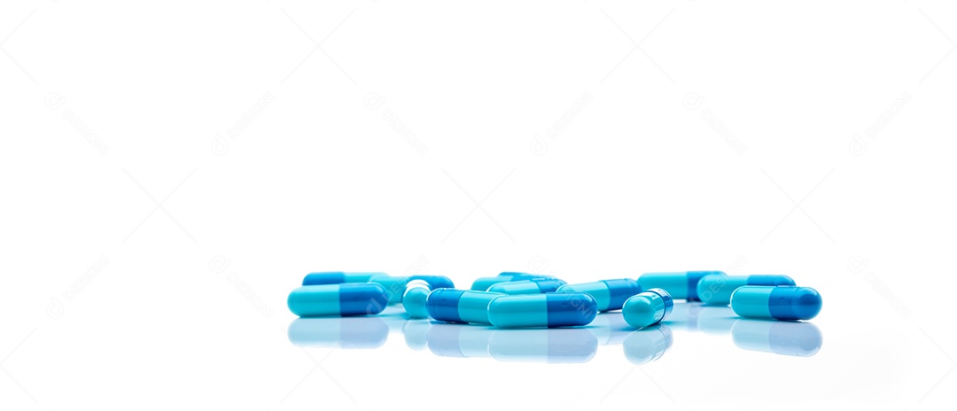 Comprimidos de cápsulas de antibióticos azuis espalhados em fundo branco.