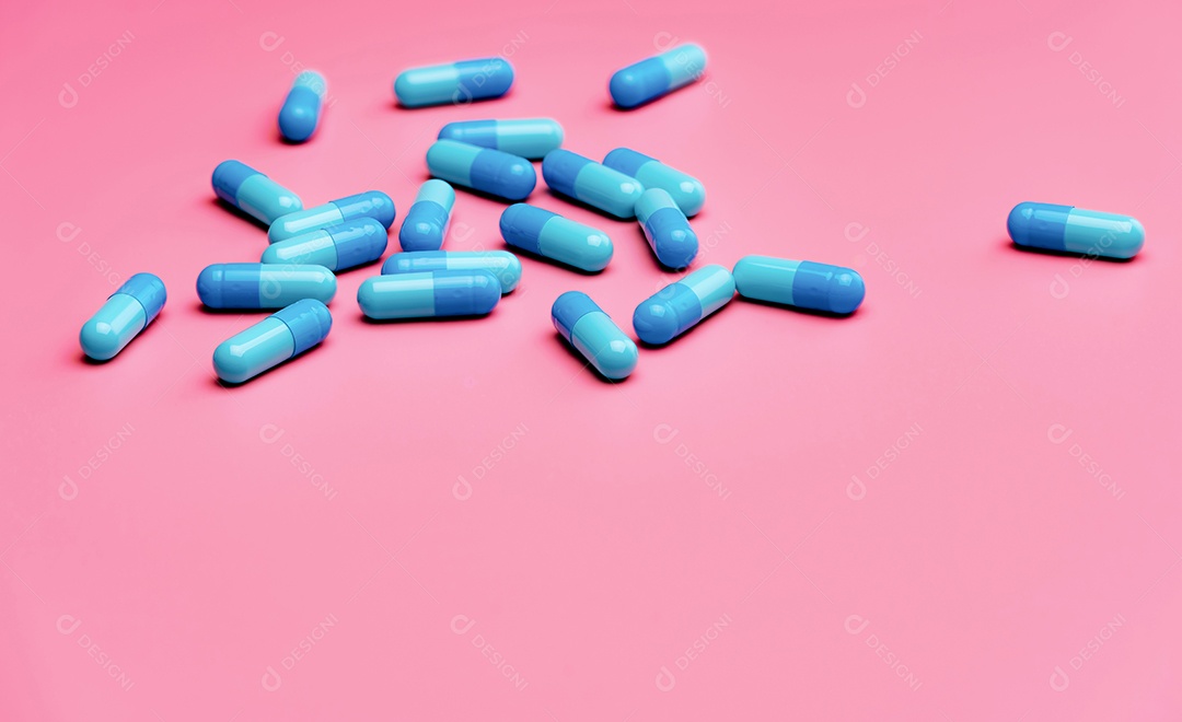 Comprimidos de cápsulas de antibióticos azuis em fundo rosa. Antibióticos azuis