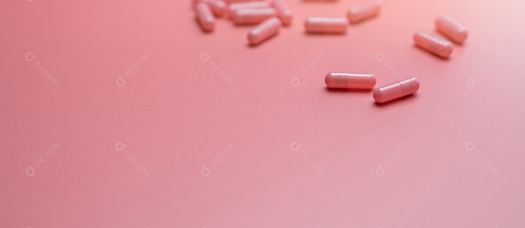 Pílula de cápsulas rosa espalhada em fundo rosa. vitaminas e suplementos