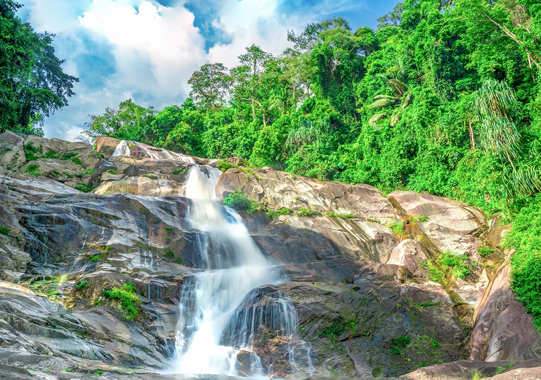 Cachoeira bonita na montanha com céu azul e cumulus branco