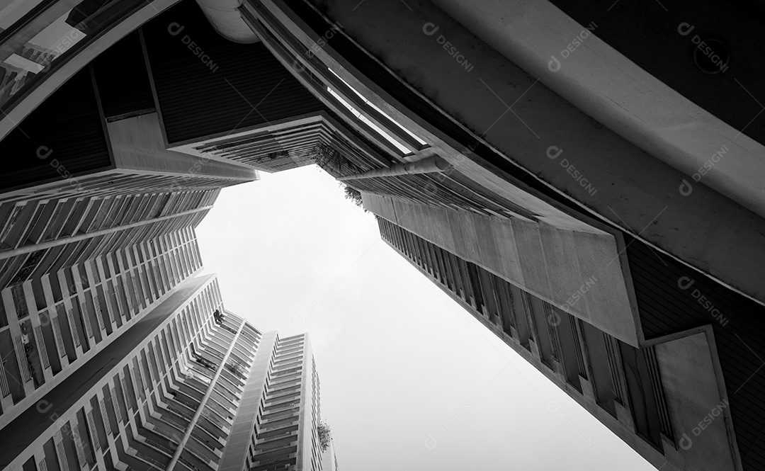 Vista inferior do edifício arranha-céu contra nuvens e céu cinza.