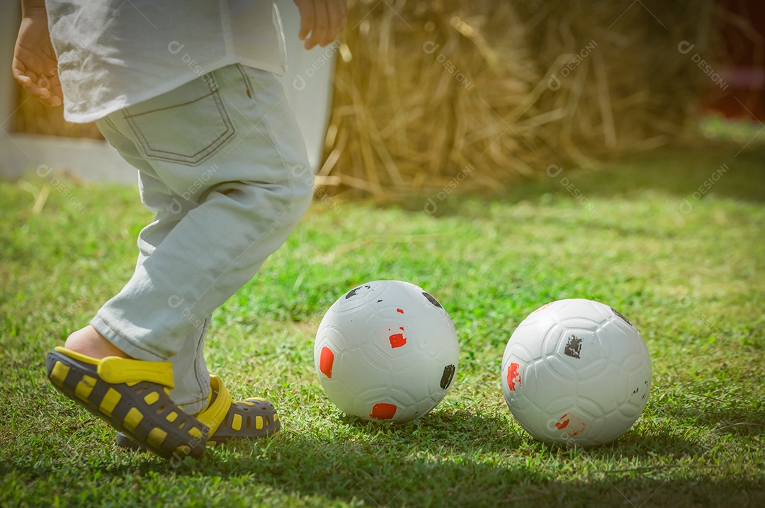 Menino bonitinho feliz jogando futebol fora de casa ou escola