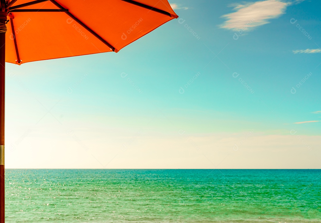 Guarda-sol laranja na praia de areia dourada à beira-mar com emera