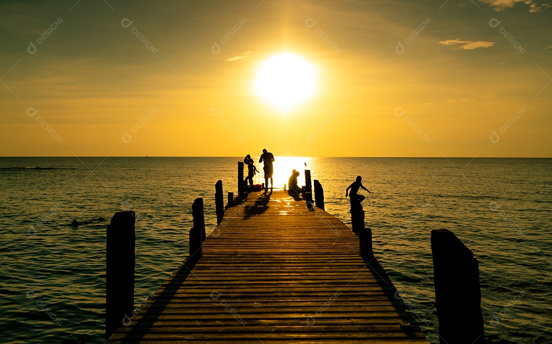 A família feliz joga junto nas férias de verão na ponte de madeira