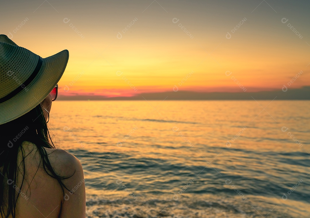 Vista traseira da mulher sexy assistindo o pôr do sol na praia. roupa de mulher