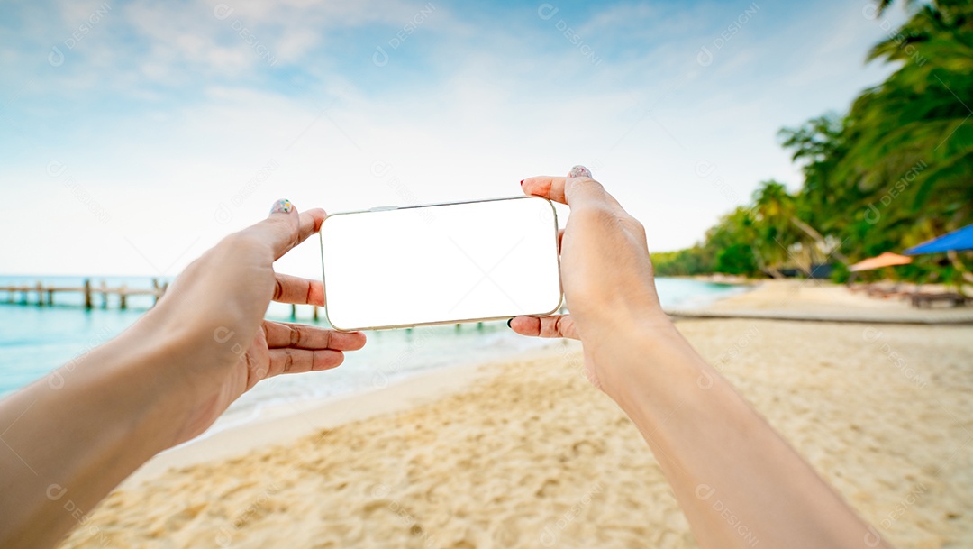 Mãos de mulher segurando smartphone com exibição de tela vazia na areia