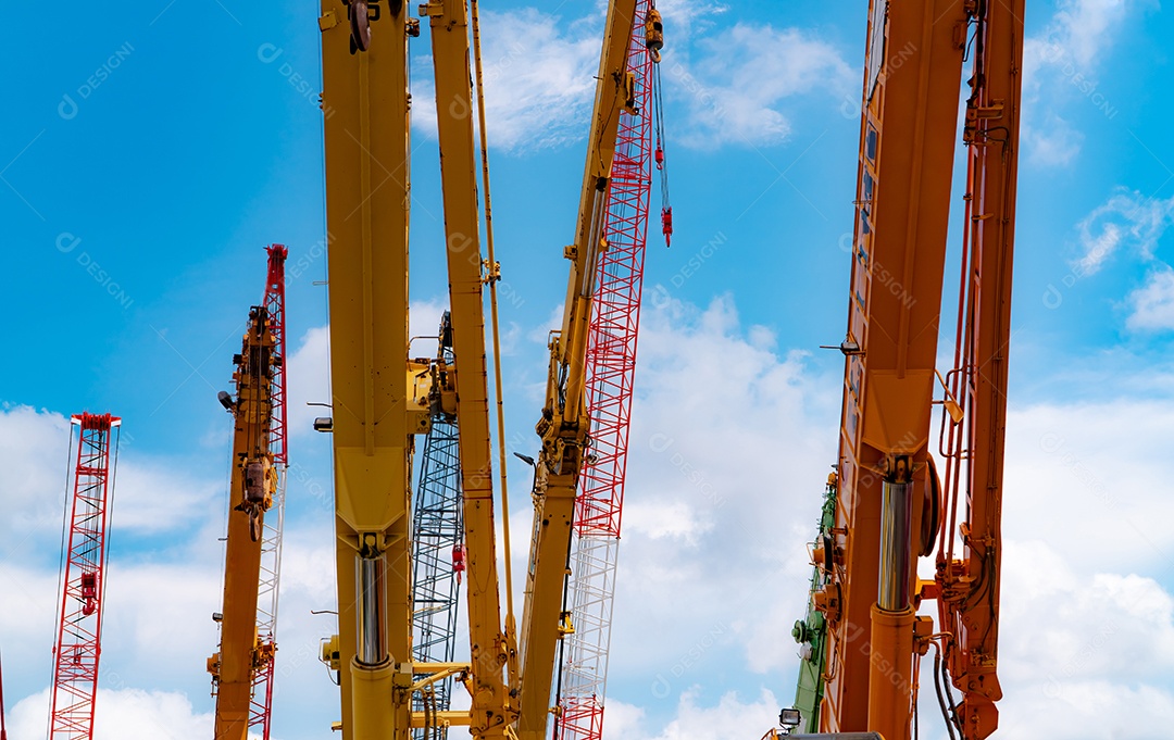 Guindaste sobre esteiras contra céu azul e nuvens brancas.