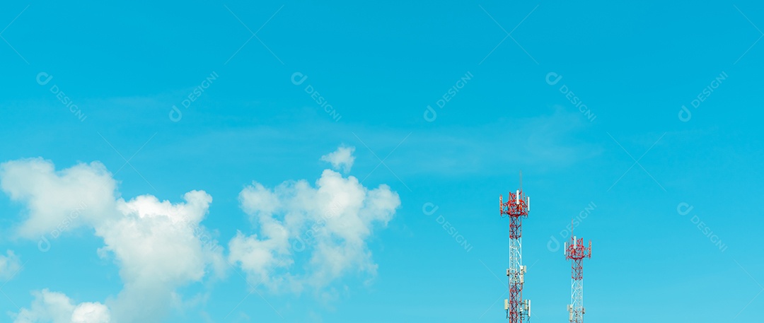 Torre de telecomunicações com céu azul e nuvens brancas.