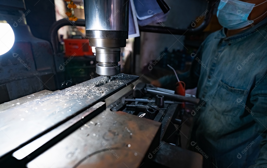 Um homem usa máscara cirúrgica trabalhando com fresadora.