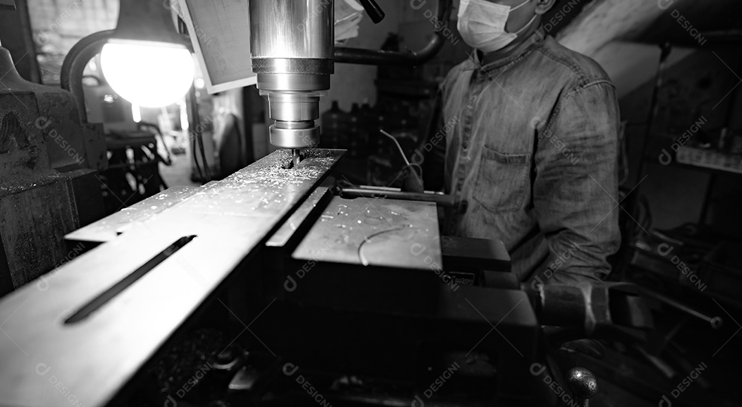 Fresadora trabalhando perto de trabalhador com máscara de proteção.