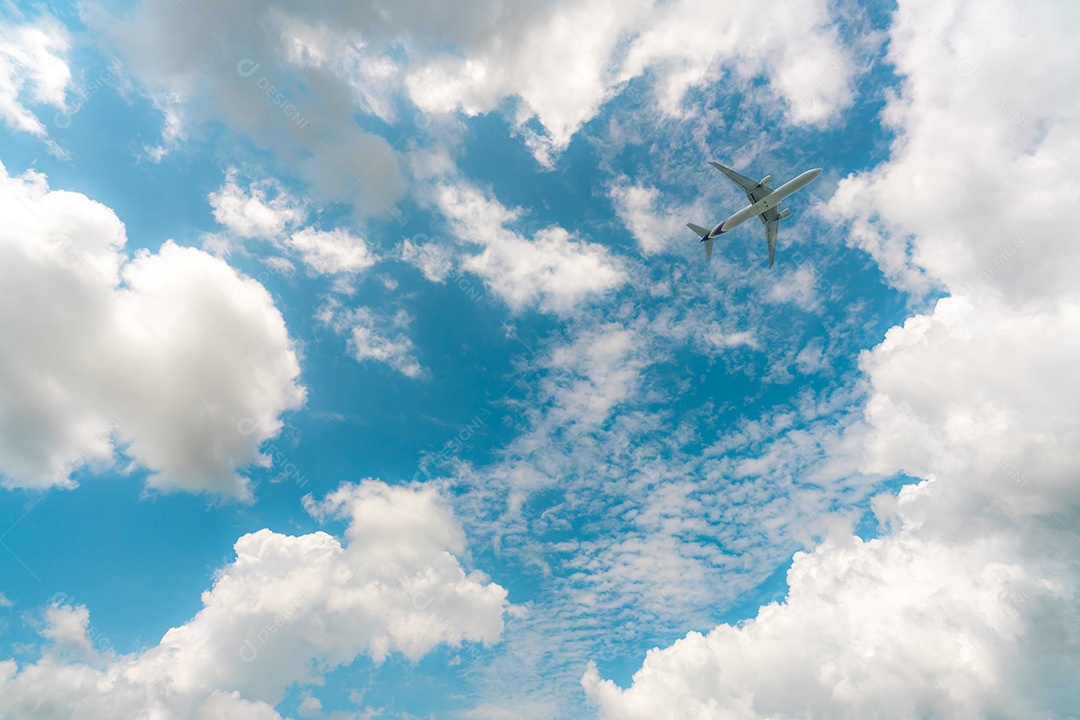 Linha aérea comercial voando no céu azul e nuvens cumulus brancas.