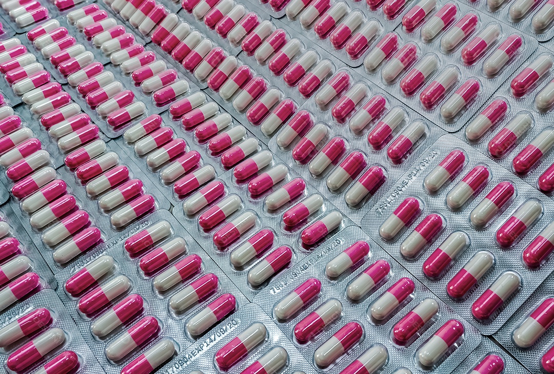 Comprimidos de cápsula de antibiótico rosa-branco closeup em blister.