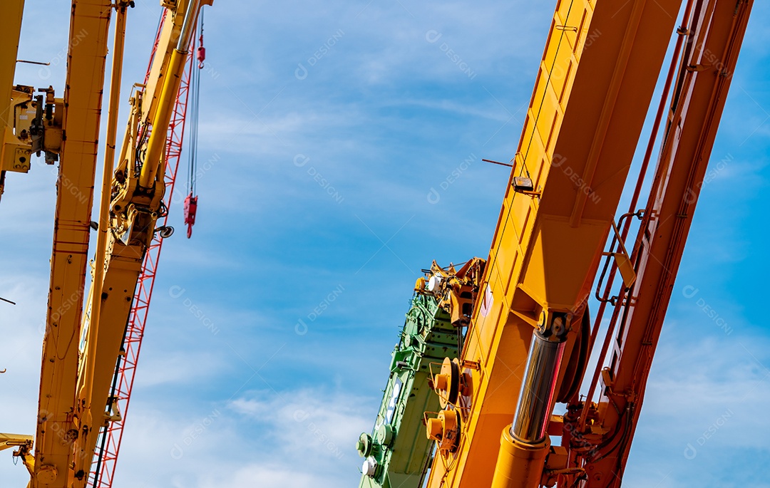 Foco seletivo no guindaste sobre esteiras contra o céu azul.