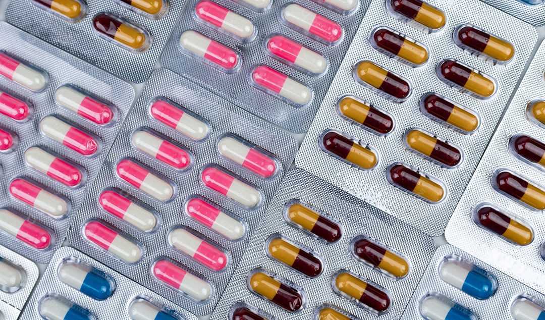 Vista superior de pílulas coloridas de cápsulas de antibióticos em blister.