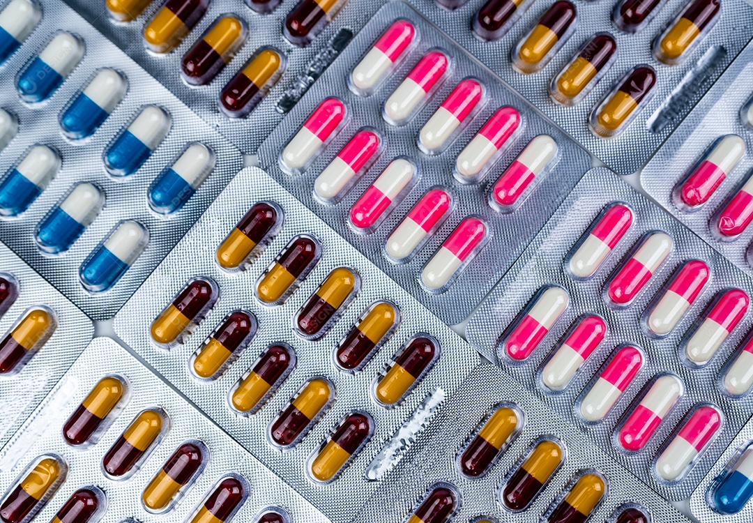 Vista superior de pílulas coloridas de cápsulas de antibióticos em blister.