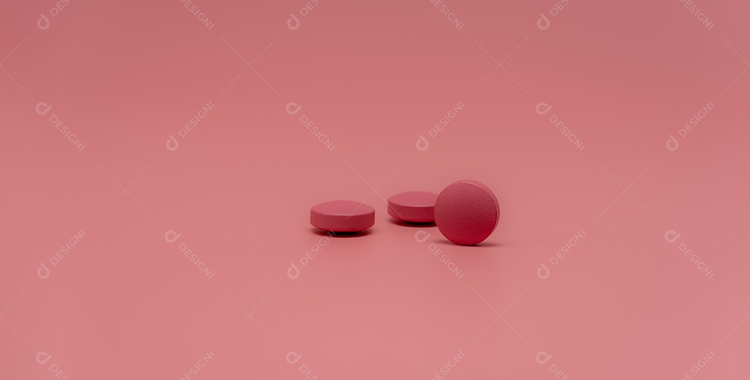 Foco seletivo na pílula de comprimido rosa redonda no fundo rosa.