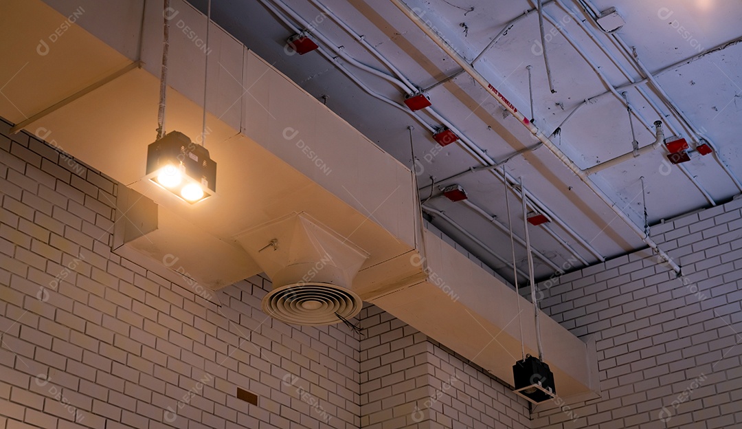 Lâmpada de teto com luz aberta e duto de ar pendurado no teto.