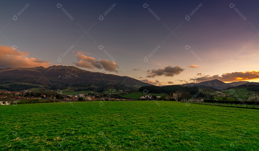 Campo de grama verde na aldeia rural perto da sagacidade do vale da montanha rochosa