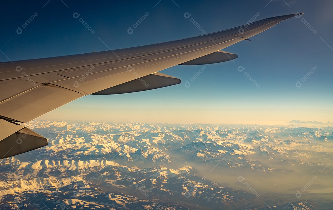 Asa de avião sobre cobertura de montanha com neve branca.