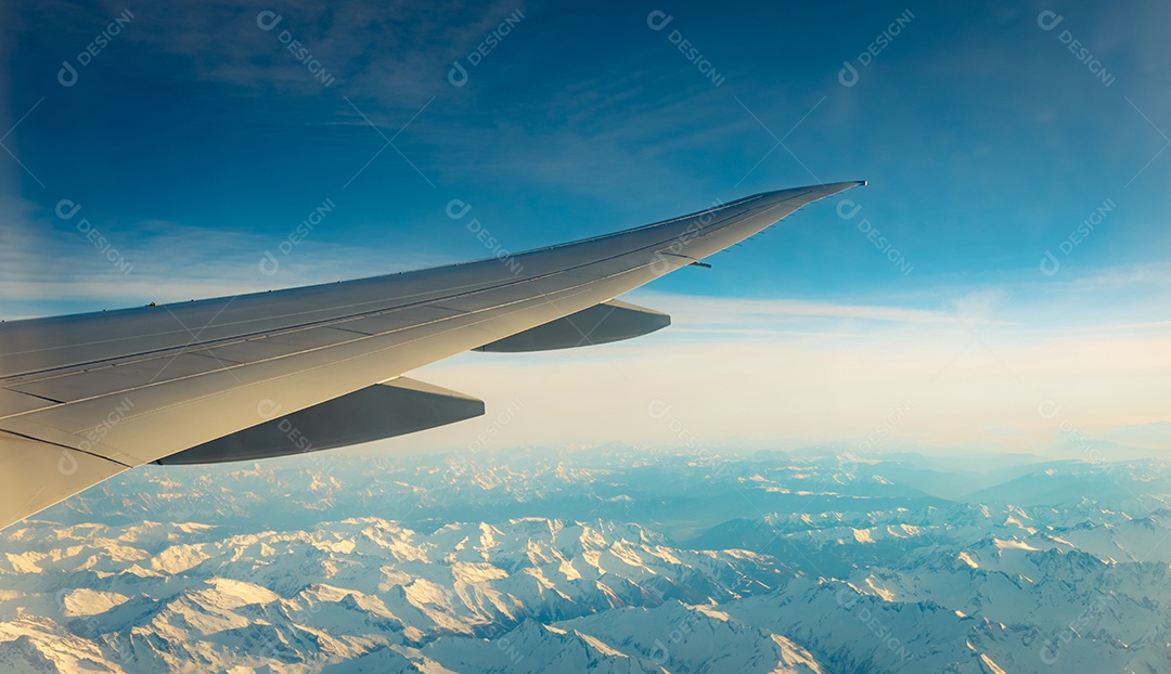 Asa de avião sobre cobertura de montanha com neve branca.