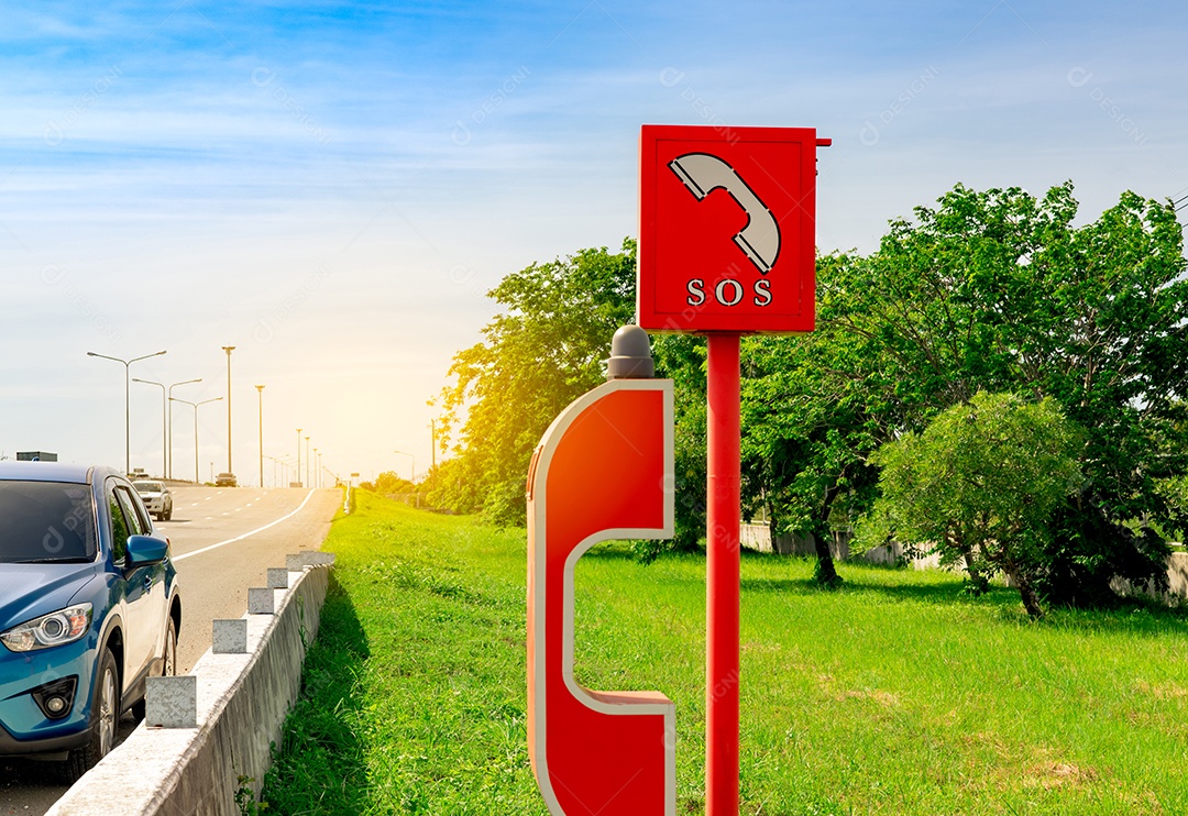 Carro SUV azul estacionado na beira da estrada perto do telefone SOS de emergência.