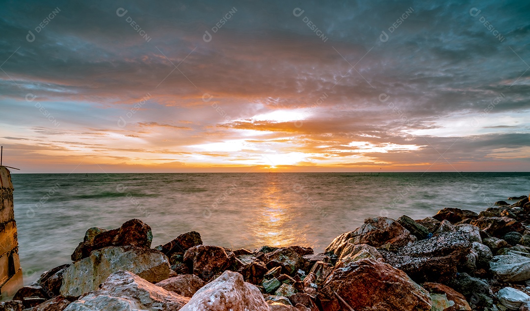 Rochas na praia de pedra ao pôr do sol. Céu do pôr do sol de praia linda.