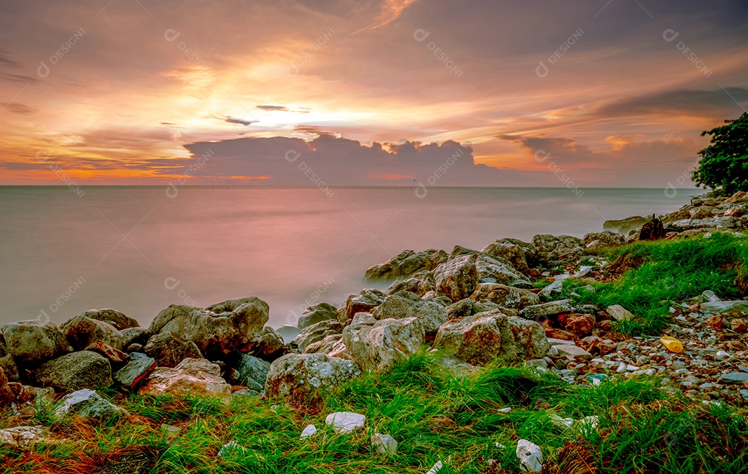 Rochas na praia de pedra ao pôr do sol. Bela paisagem de mar calmo.