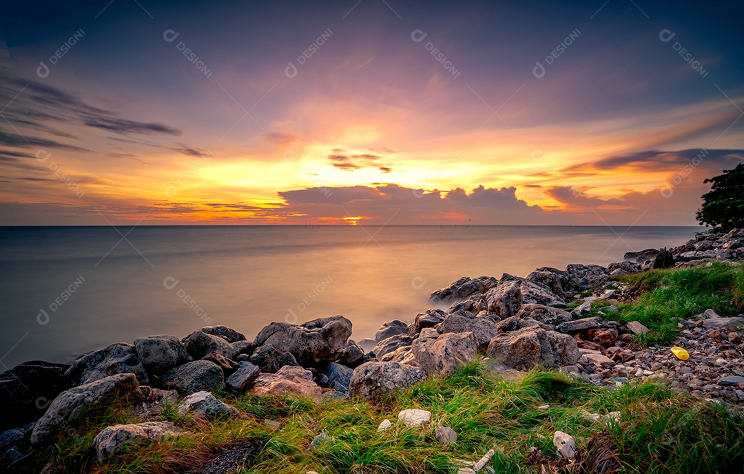 Rochas na praia de pedra ao pôr do sol. Bela paisagem de mar calmo.