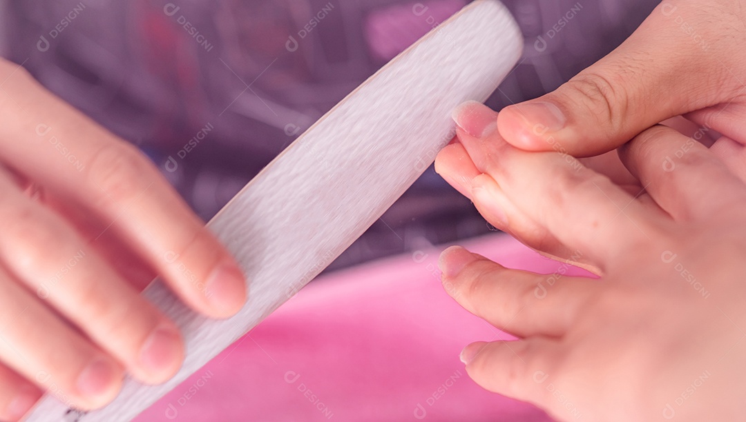 Mulher recebendo serviço de manicure de unha por profissional