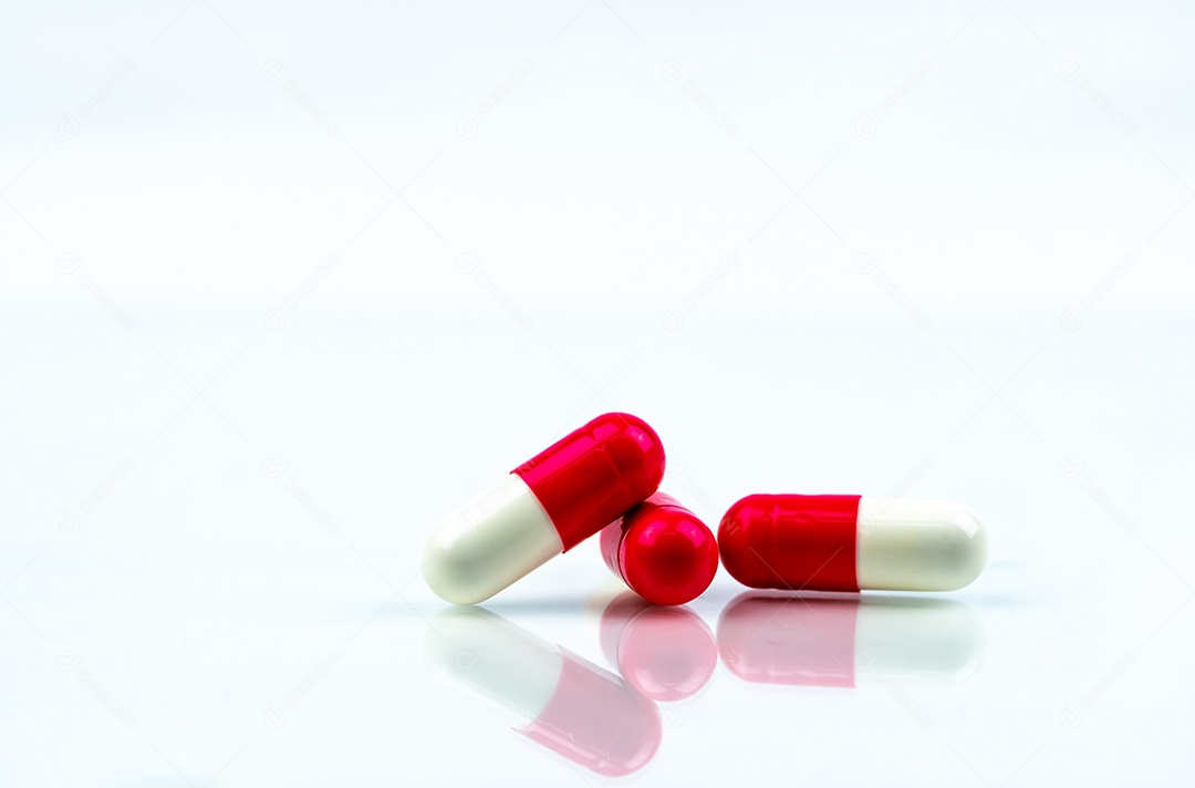 Comprimido vermelho e branco das cápsulas isolado no fundo branco