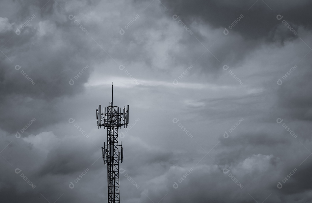 Torre de telecomunicações com fundo de céu escuro e nuvens brancas