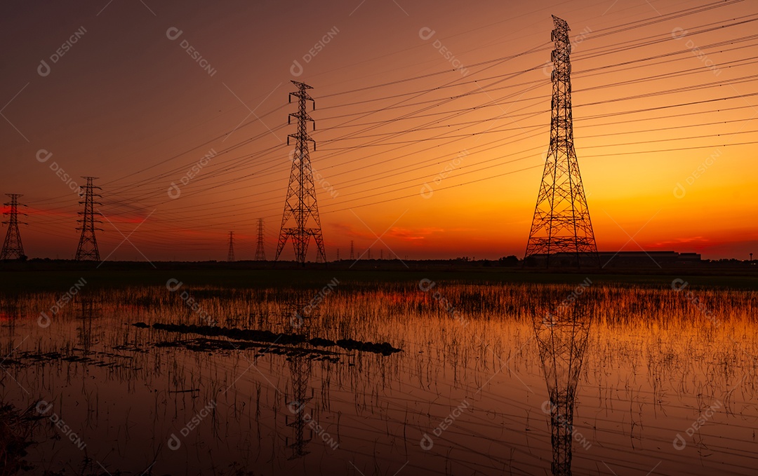 Pilão elétrico de alta tensão e fio elétrico com céu pôr do sol.