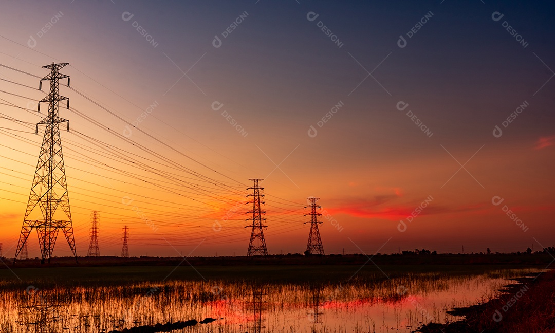 Pilão elétrico de alta tensão e fio elétrico com céu pôr do sol.