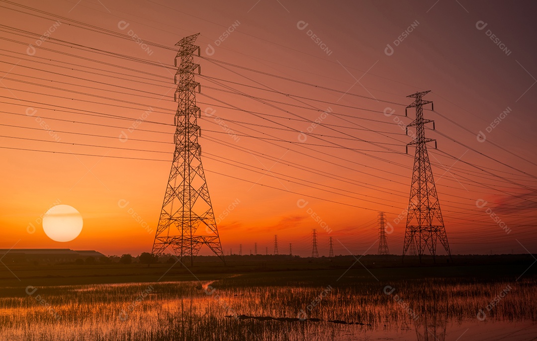 Pilão elétrico de alta tensão e fio elétrico com céu pôr do sol.