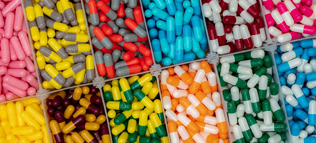Comprimidos coloridos da cápsula na caixa plástica. Indústria farmacêutica.