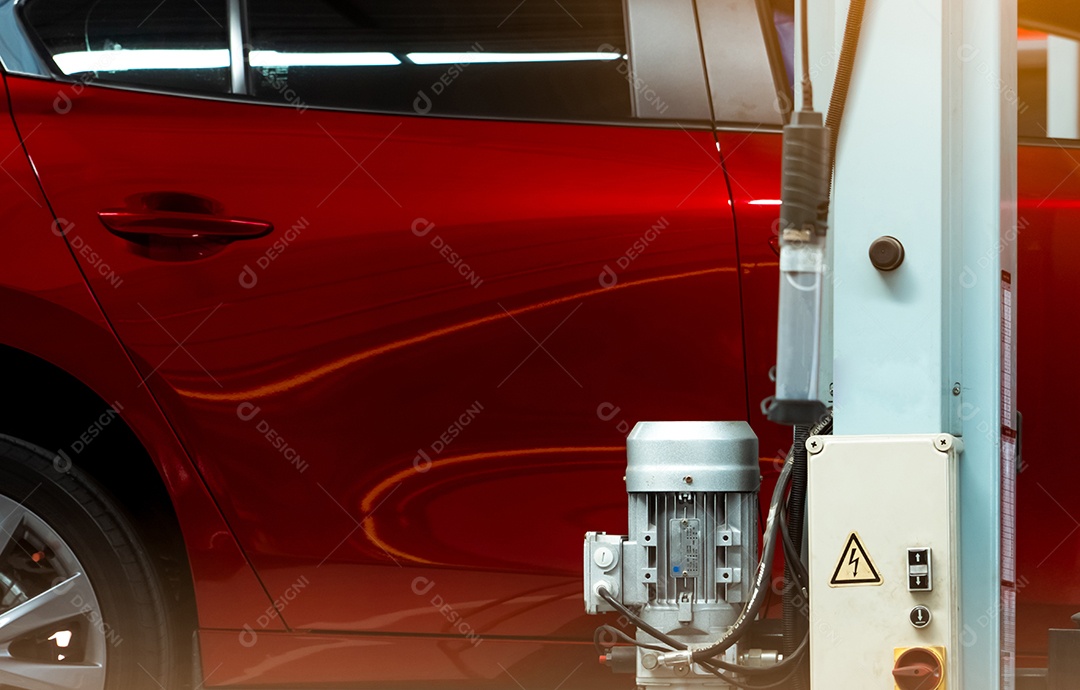 Foco seletivo no carro brilhante vermelho e no poste da máquina de elevação