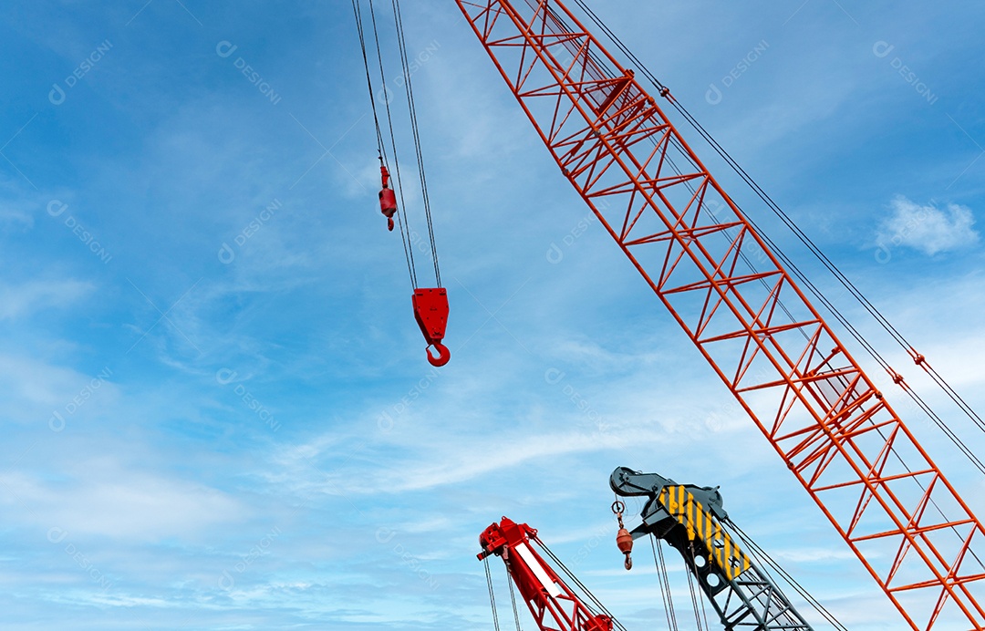 Guindaste sobre esteiras contra céu azul e nuvens brancas.