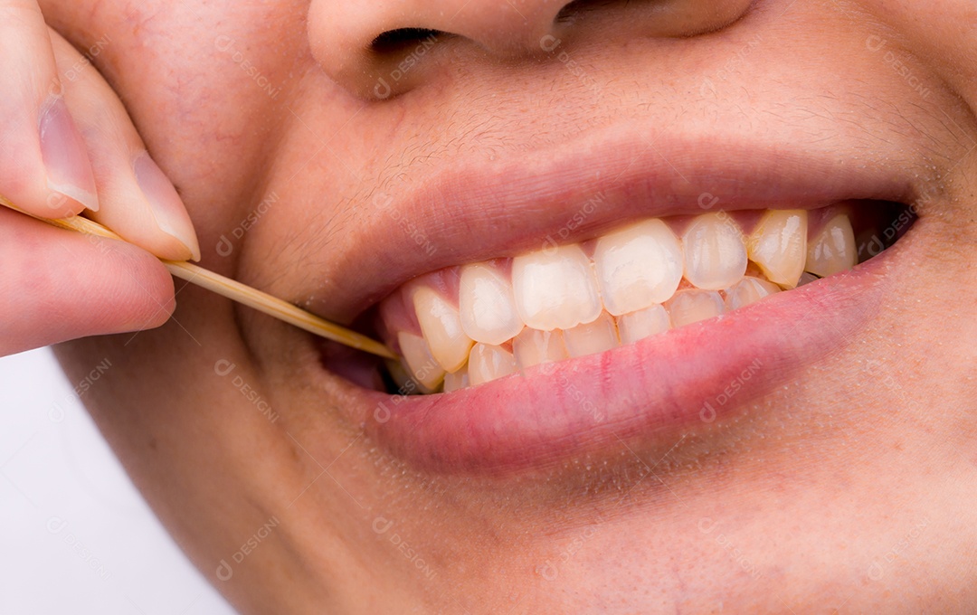 Mulher asiática limpa os dentes da comida enfiada nos dentes com bambu
