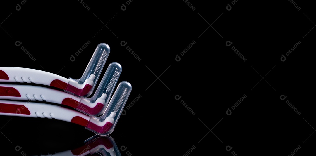 Três escovas interdentárias com tampa isolada em fundo preto