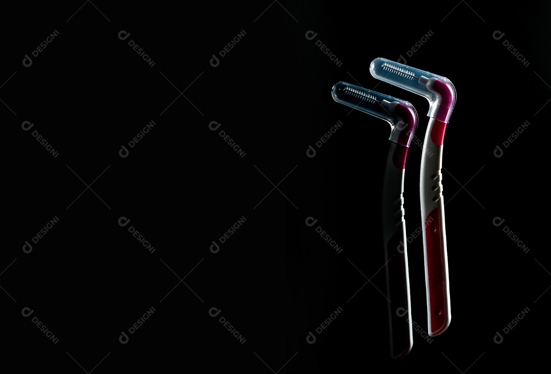 Duas escovas interdentárias com tampa isolada em fundo escuro