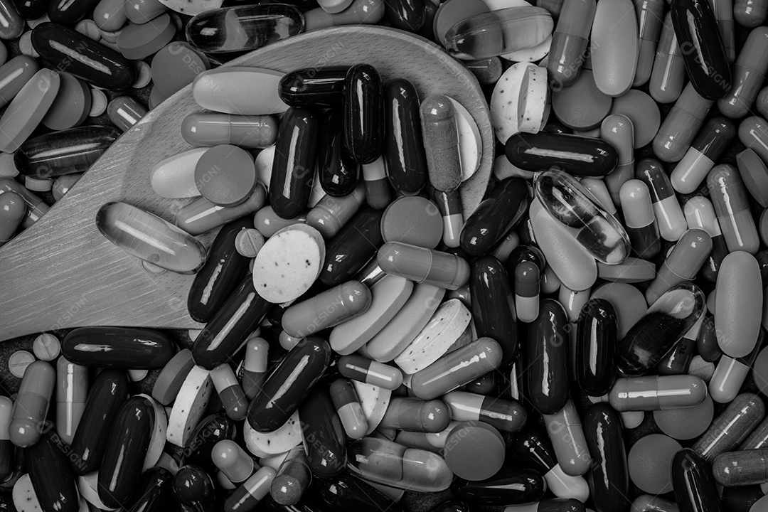 Muitos comprimidos e cápsulas e colher de madeira em preto