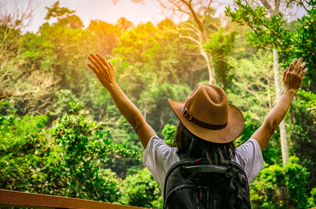 Turista de mulher feliz com chapéu e mochila em pé