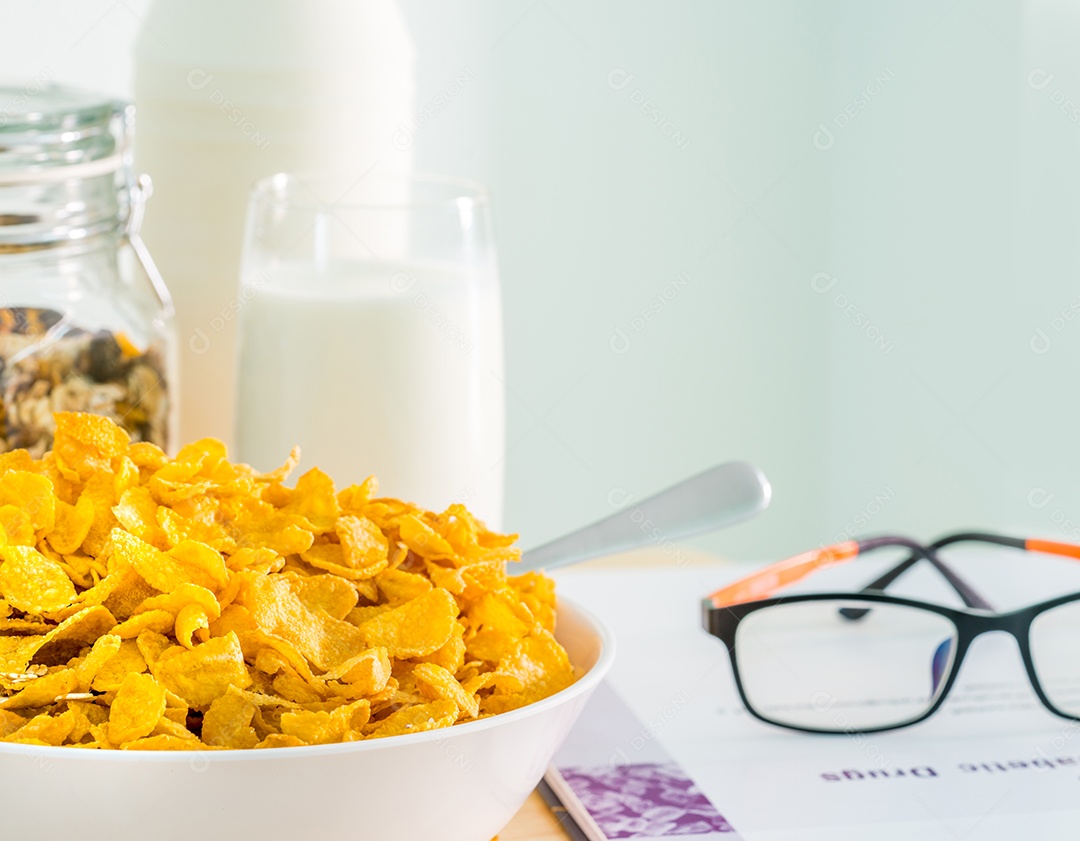 Tigela de cereal com colher e um copo de leite colocado na mesa de madeira